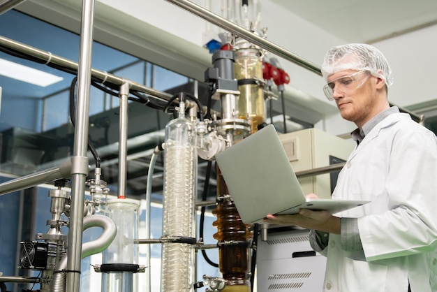 Foto apothekerwetenschapper die gegevens opneemt van cbd-olie-extractor in laboratorium