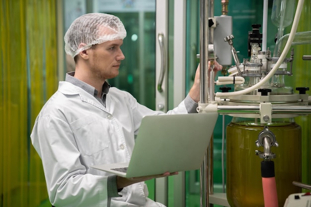 Foto apothekerwetenschapper die gegevens registreert van cbd-olie-extractor in laboratorium