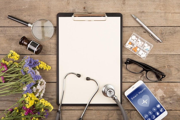 App voor gezondheidsbewakingsconcept smartphone stethoscoop noodpakket en andere dingen op houten bureau