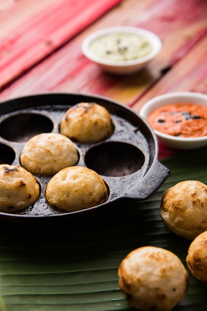 Appam or Mixed dal or Rava Appe served over moody background with green and red chutney. A Ball shape popular south Indian breakfast recipe. Selective focus