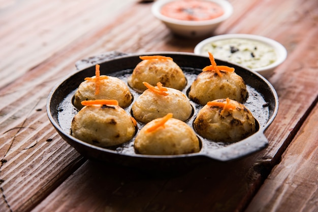 Appam or Mixed dal or Rava Appe served over moody background with green and red chutney. A Ball shape popular south Indian breakfast recipe. Selective focus