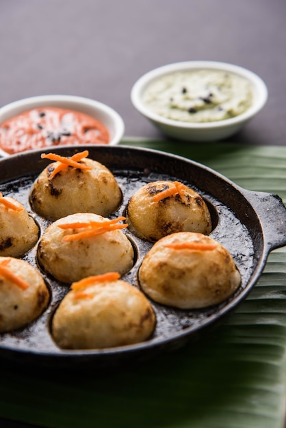 Appam or Mixed dal or Rava Appe served over moody background with green and red chutney. A Ball shape popular south Indian breakfast recipe. Selective focus