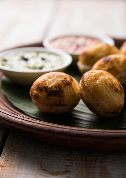 Appam of Mixed dal of Rava Appe geserveerd op een humeurige achtergrond met groene en rode chutney. Een populair Zuid-Indiaas ontbijtrecept in de vorm van een bal. Selectieve focus