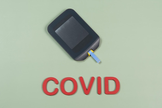 Apparaat om bloedglucose te meten en het woord Covid geschreven