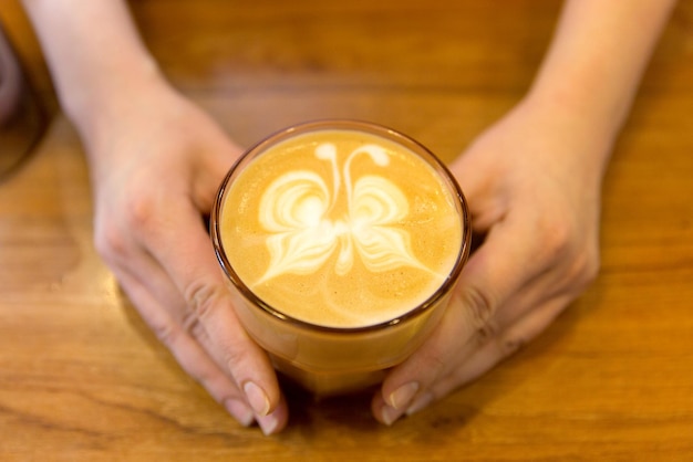 apparatuur, coffeeshop, mensen en technologie concept - close-up van handen met latte art ets in koffiekopje