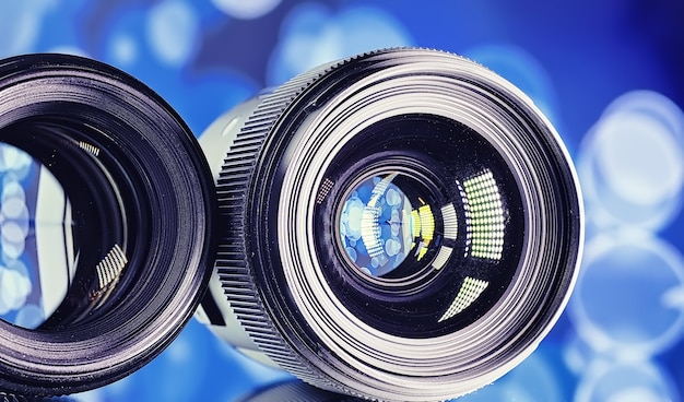 Apparatuur videograaf en fotograaf. Lenzen op tafel tegen de achtergrond van felle lampen. Schittering en bokeh in de reflectie van het cameraglas.