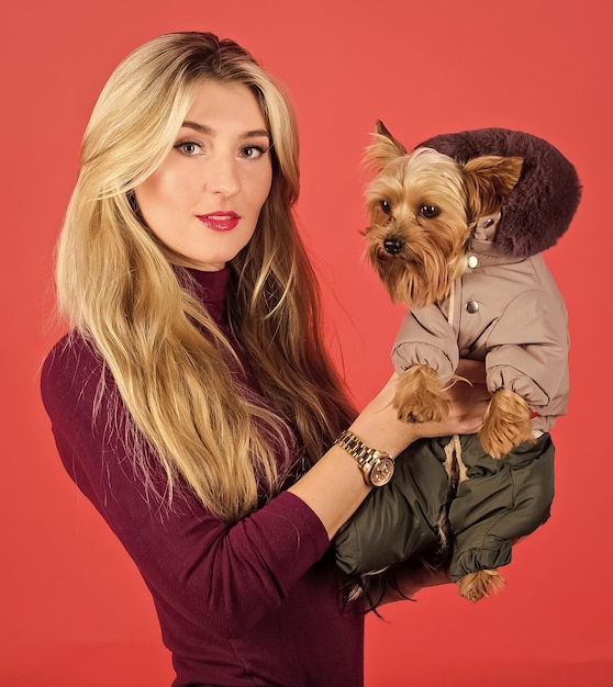 Apparel and accessories Which dog breeds should wear coats Girl hug little dog in coat Woman carry yorkshire terrier Dressing dog for cold weather Make sure dog feel comfortable in clothes