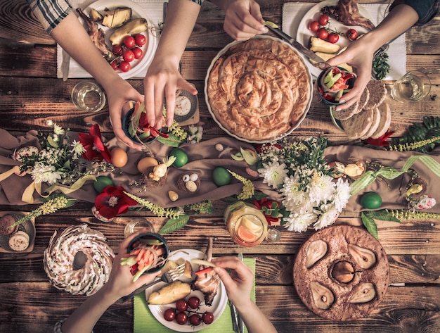 Foto appartement-feest van vrienden of familie aan de feestelijke tafel met konijnenvlees, groenten, taarten, eieren, bovenaanzicht.