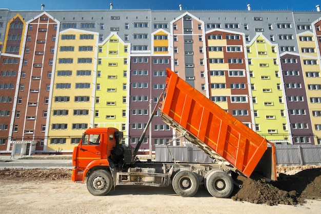 Appartementengebouw met meerdere verdiepingen en dumptruck lossen grond
