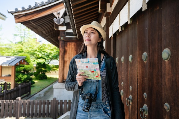 appealing asian traveler visiting the old japanese traditional building with a guidemap.