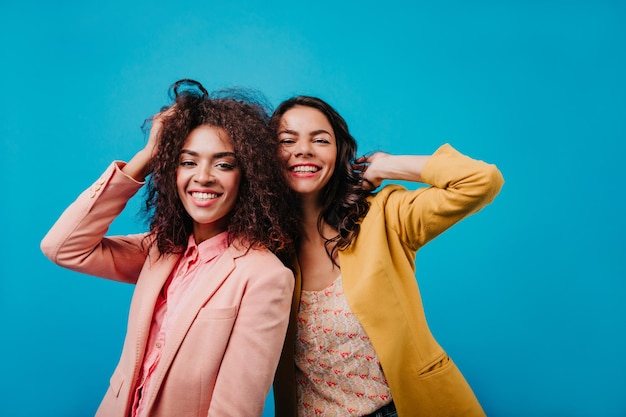 Photo appealing lady in pink jacket playing with her hair international friends laughing on blue background