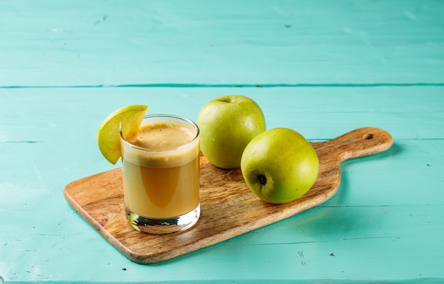 Foto appel- en gembersap met rauwe appels geserveerd in een glas geïsoleerd op snijplank zijaanzicht gezond vruchtensap