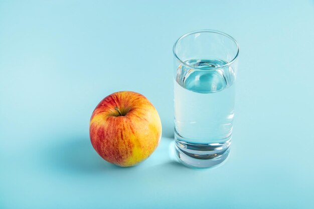 Foto appel en glas zuiver water op een blauwe achtergrond gezondheid en dieet voedsel concept