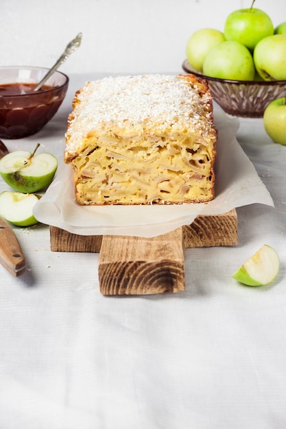 Appel- en kokosnootcake op houten snijplank en appels in een vaas. Ruimte kopiëren