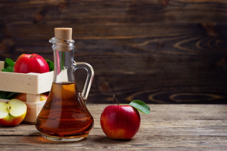 Appelazijn en verse rode appel op een houten achtergrond