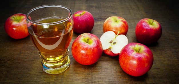 appelciderazijn in een glas met appels op de houten vloer