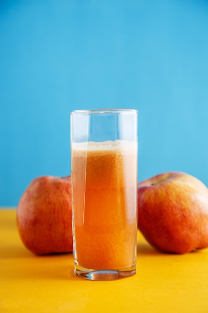 Appels en een glas natuurlijk appelsap op geelblauw