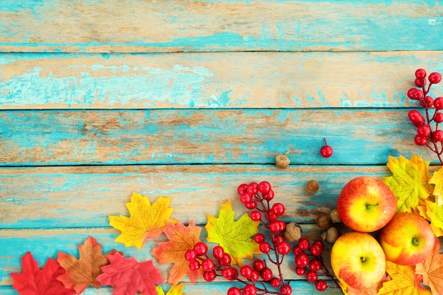 Foto appels en rode bessen op houten tafel over esdoorn bladeren