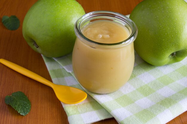 Appels puree in de pot en groene appels op tafel