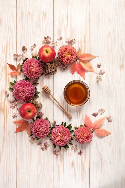 Appels, roze bloemen en honing met kopie ruimte vormen een florale decoratie.