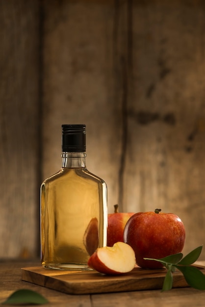 Appelsap in een fles en glas met gesneden rode appel op houten achtergrond