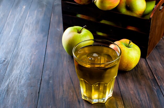 Appelsap in een glas en een rijpe appels op een houten tafel
