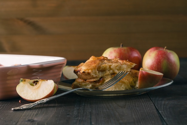 Appeltaart met appelschijfjes en krokante korst op een houten tafel. Zelfgemaakte desserts.