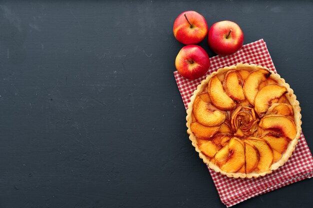 Appeltaarttaart en rode appels op houten tafel