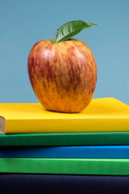 Foto appelvrucht op de top van een boekstapel aan de achterzijde van schoolklassen