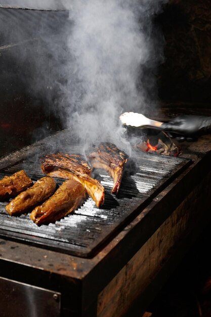 Appetitieuze sappige tomahawk steaks ribeye en sirloin op een barbecue grill over een brandende vlam terwijl het grillen van gegrilde vlees in een restaurant