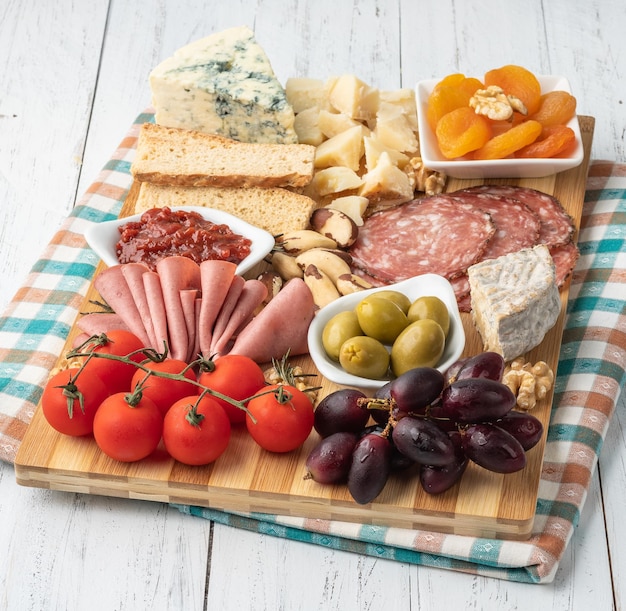 Appetizer board with cheese nuts fruits toasts and charcuterie over wooden table