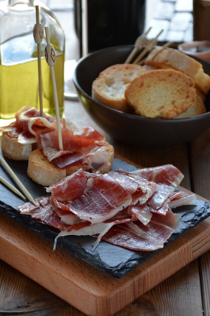 Appetizer of ham Serrano with bread roasted and accompanied by a glass of wine