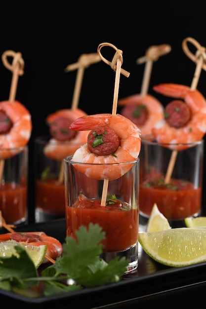 Appetizer of shish kebab with shrimps and chorizo sausages with barbecue sauce in a glass