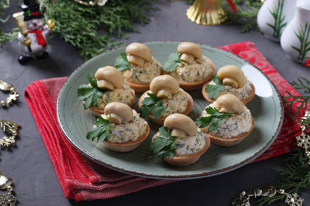 Закуска в тарталетках с грибами, яйцом и сыром на сером фоне.