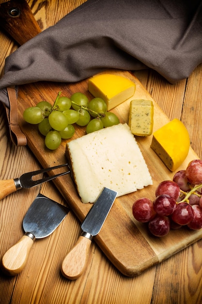 Appetizer with cheese and grapes on a wooden kitchen board