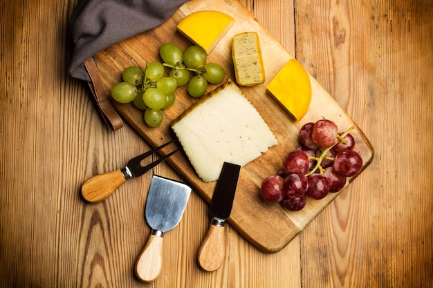 Photo appetizer with cheese and grapes on a wooden kitchen board