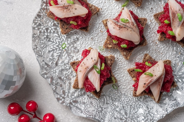 Appetizer with Herring fillet with beetroot spread, onion and black bread.