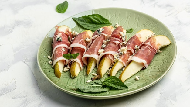 Appetizer with pear blue cheese and prosciutto ham on a dark background Healthy fats clean eating for weight loss Long banner format top view