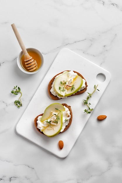 Appetizer with ricotta cheese cream honey pear thyme on white board Toast snack bruschetta