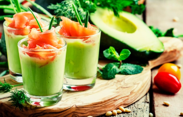 Appetizer with smoked salmon and avocado mousse served in glasses vintage wooden background selective focus