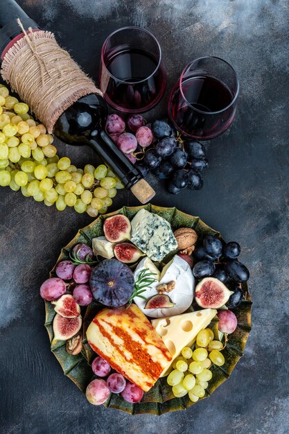 Appetizers table with italian antipasti snacks and wine in\
glasses cheese ham nuts fruit bread sticks delicious balanced food\
concept vertical image top view