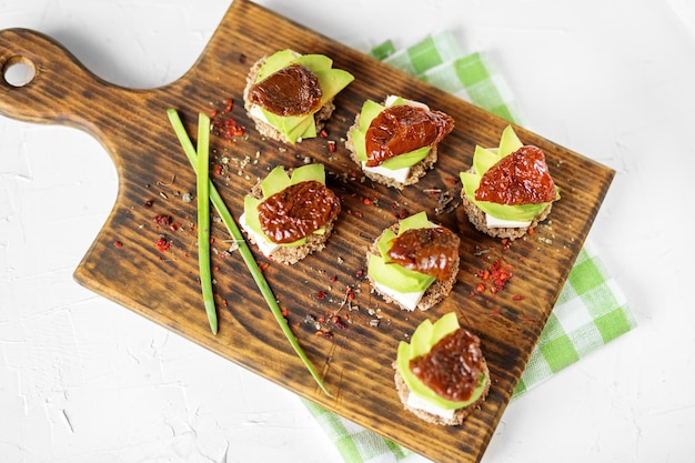 Appetizers with cheese avocado and dried tomatoes on the board Concept for food healthy food