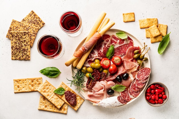 Antipasti con diversi antipasti, spuntini e vino rosso su sfondo bianco prosciutto di salsiccia