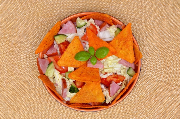 Foto insalata di stuzzichini appetitosi con patatine di nachos in una ciotola su uno sfondo chiaro piatto