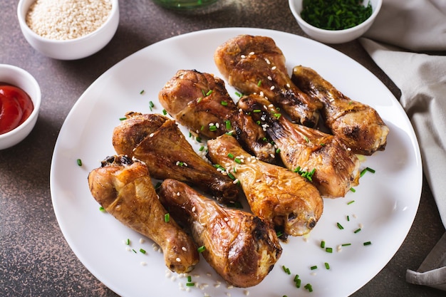 Appetizing baked chicken legs with chives and sesame seeds on a plate