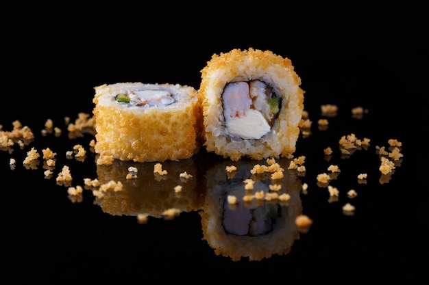 Appetizing baked sushi roll with fish on a black background with reflection