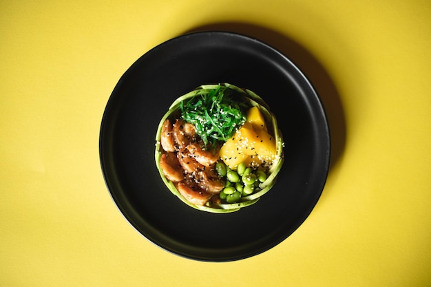 Appetizing bowl with meat and vegetables sprinkled with sesame seeds on an orange background