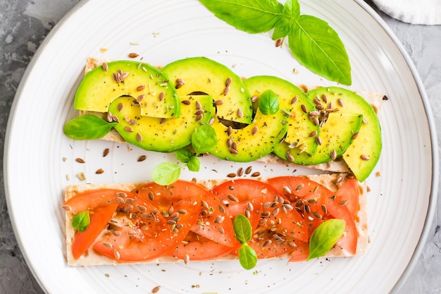 Appetizing bruschetta with avocado and tomatoes on grain bread on a plate on the table Vegetarian healthy food Top view Closeup