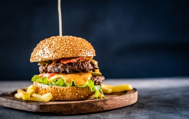 Appetizing burger and french fries on wooden board