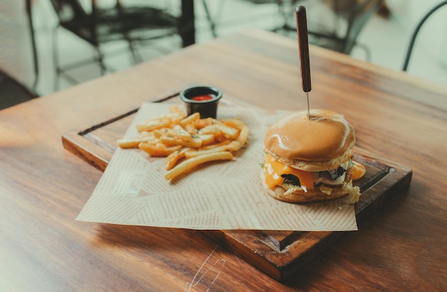 Appetizing burger with fries served on a wooden table Traditional hamburger with fries served on a restaurant table